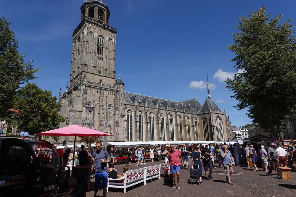Kramen van de Deventer Boekenmarkt met bezoekers, met de Lebuïnustoren erachter